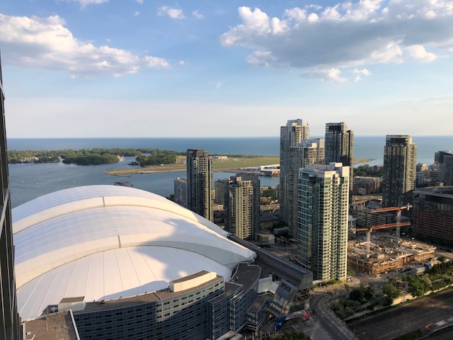 High-floor panoramic view from 300 Front St W overlooking the Rogers Centre, Billy Bishop Airport, and the Toronto Islands against the Lake Ontario horizon.